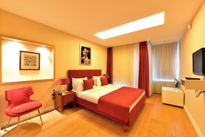 A hotel room with a bed, a red chair, a desk, and a TV. - Cheya Residences Nisantasi Deluxe (Istanbul)