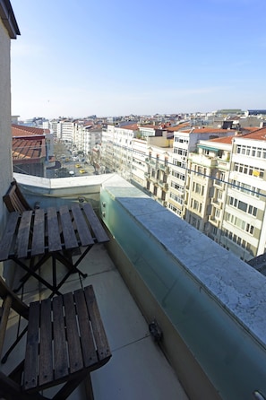 Enjoy the city view from this balcony with a table and chairs.