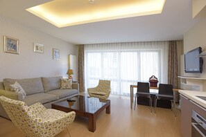 A modern living room with a sofa, patterned armchairs, a coffee table, and a television. - Cheya Residences Nisantasi Deluxe (Istanbul)