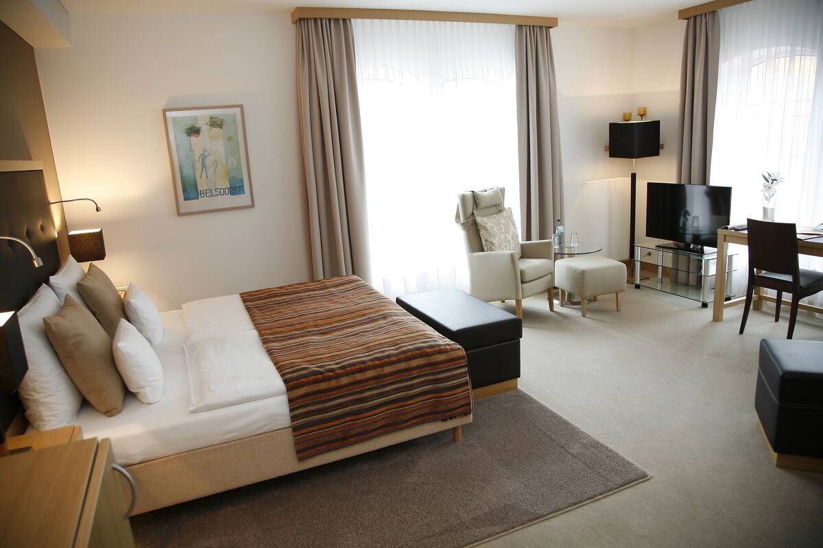 Una habitación de hotel con cama, escritorio, televisor y silla.