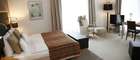 A hotel room with a bed, a desk, a television, and a chair.