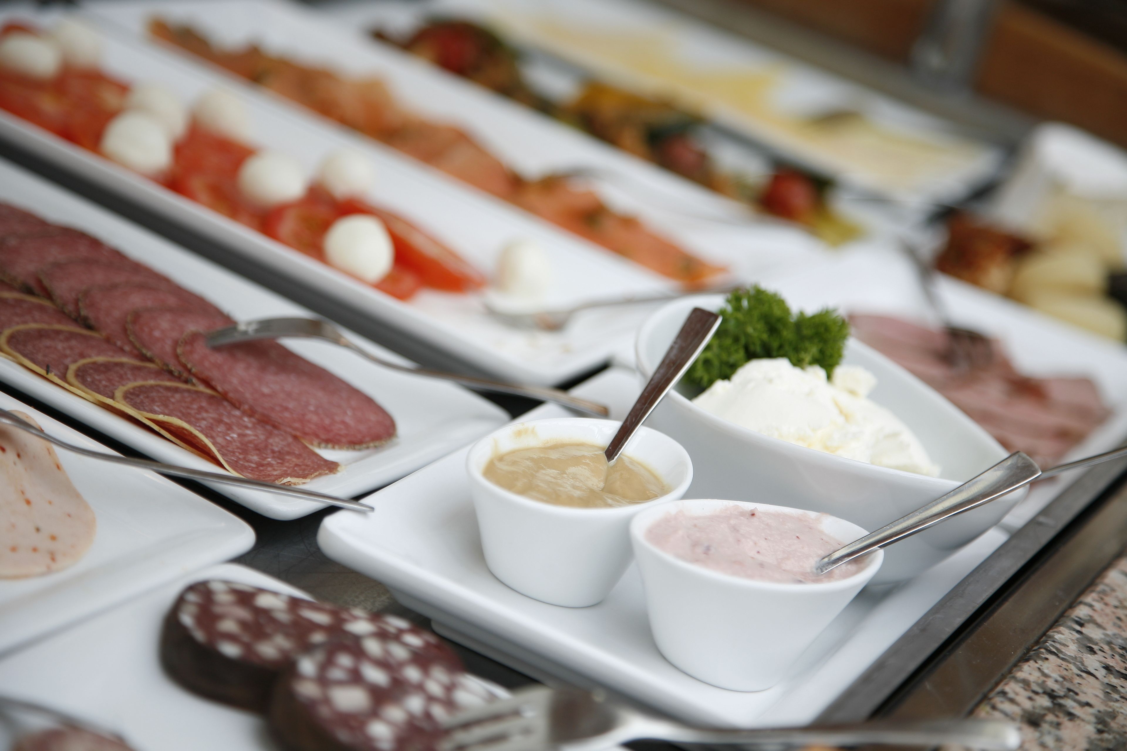 Ein Buffet mit verschiedenen Speisen, darunter Fleisch, Käse und Dips.
