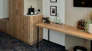 Una habitación moderna con un armario de madera, un escritorio con televisor de pantalla plana y fotografías enmarcadas en la pared.