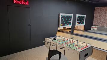 Enjoy a game of foosball or bowling in this room, which offers a unique entertainment space with a Red Bull sign.