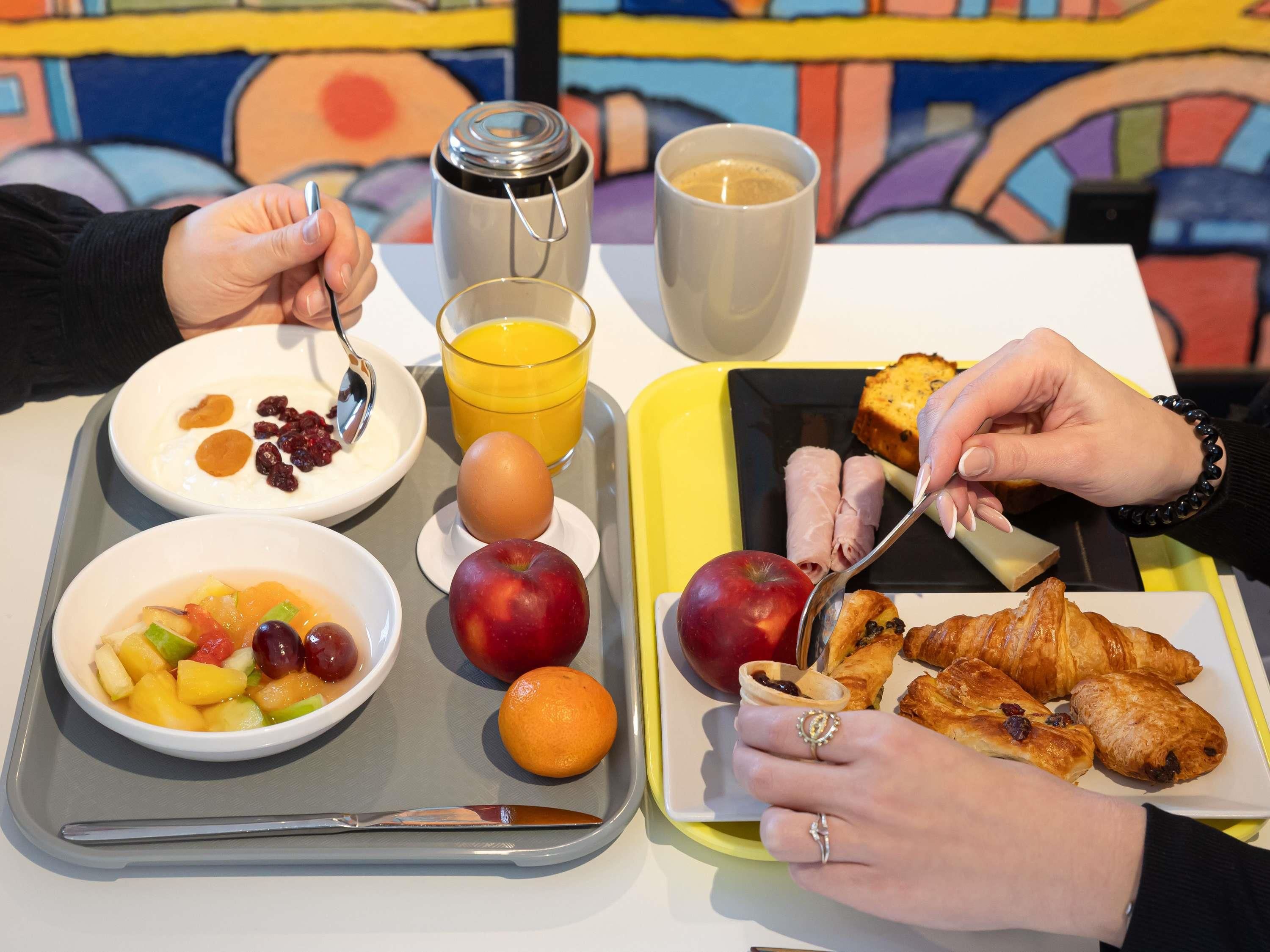 A tray with breakfast items including fruits, a glass of orange juice, and pastries.