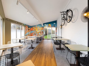 A restaurant interior with a mural, tables, chairs, and a bicycle mounted on the wall. - Ibis Styles Lille Villeneuve d’Ascq (Villeneuve-d'Ascq)