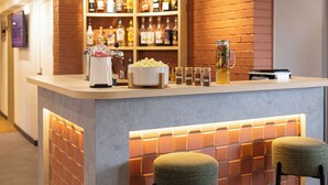 Un espace bar comprenant un comptoir, des sièges et une variété de bouteilles et de verres.