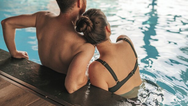 A couple sitting by a poolside with a view of a brick wall and a window. - Le Dracy (Dracy-le-Fort)