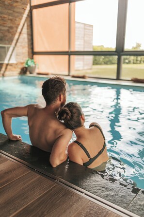 A couple sitting by a poolside with a view of a brick wall and a window. - Le Dracy (Dracy-le-Fort)