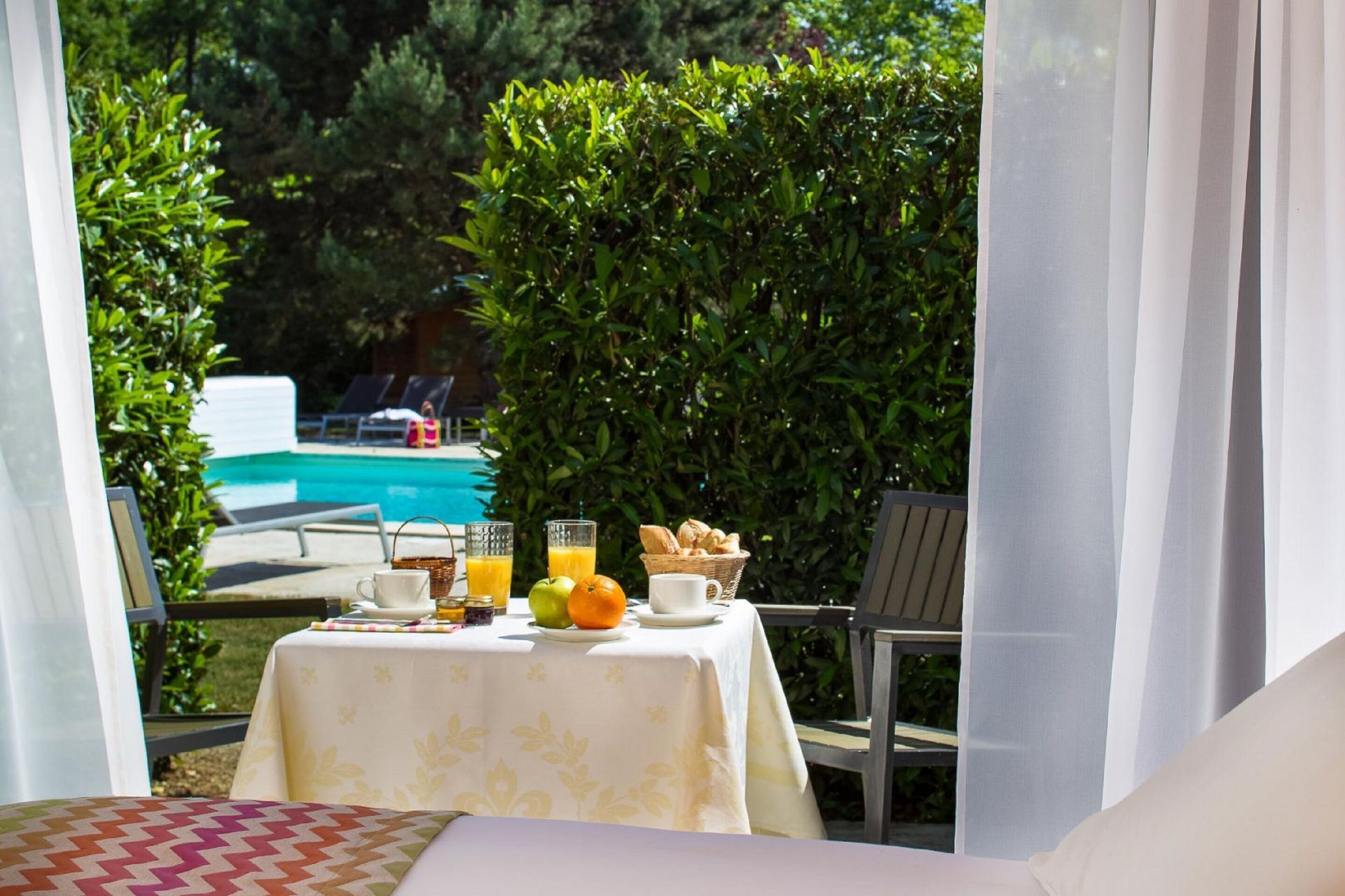 Una mesa servida con alimentos para el desayuno, una piscina y vistas a una zona junto a la piscina.