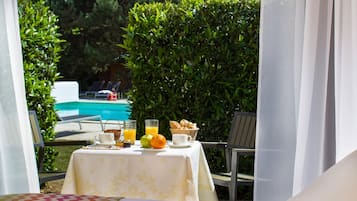 Una mesa servida con alimentos para el desayuno, una piscina y vistas a una zona junto a la piscina.