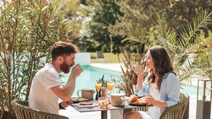Two people dining at an outdoor table with a pool in the background. - Le Dracy (Dracy-le-Fort)