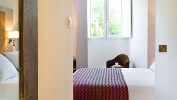 Ein Hotelzimmer mit Bett, Stuhl, Tisch, Fenster und Lampe.