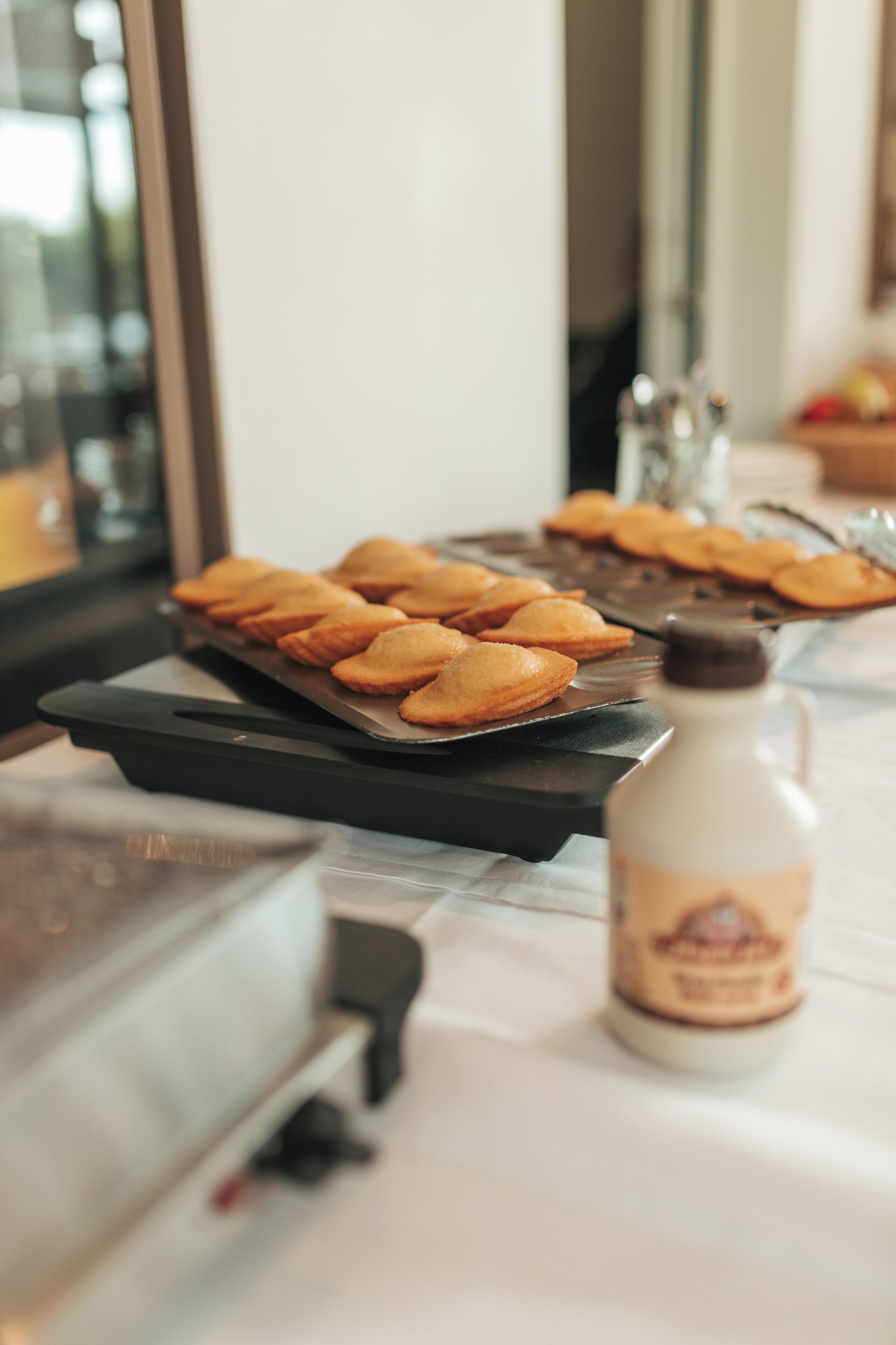 Un plateau de pâtisseries sur une table, avec une bouteille de sirop à côté.