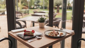 A table with a dessert and a plate of food, a napkin, and a spoon. - Le Dracy (Dracy-le-Fort)