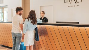 A reception area with a receptionist, a man and a woman standing in front of a reception desk. - Le Dracy (Dracy-le-Fort)
