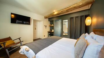 Une chambre à coucher comprenant un lit, un banc en bois, un bureau, un miroir et un téléviseur.