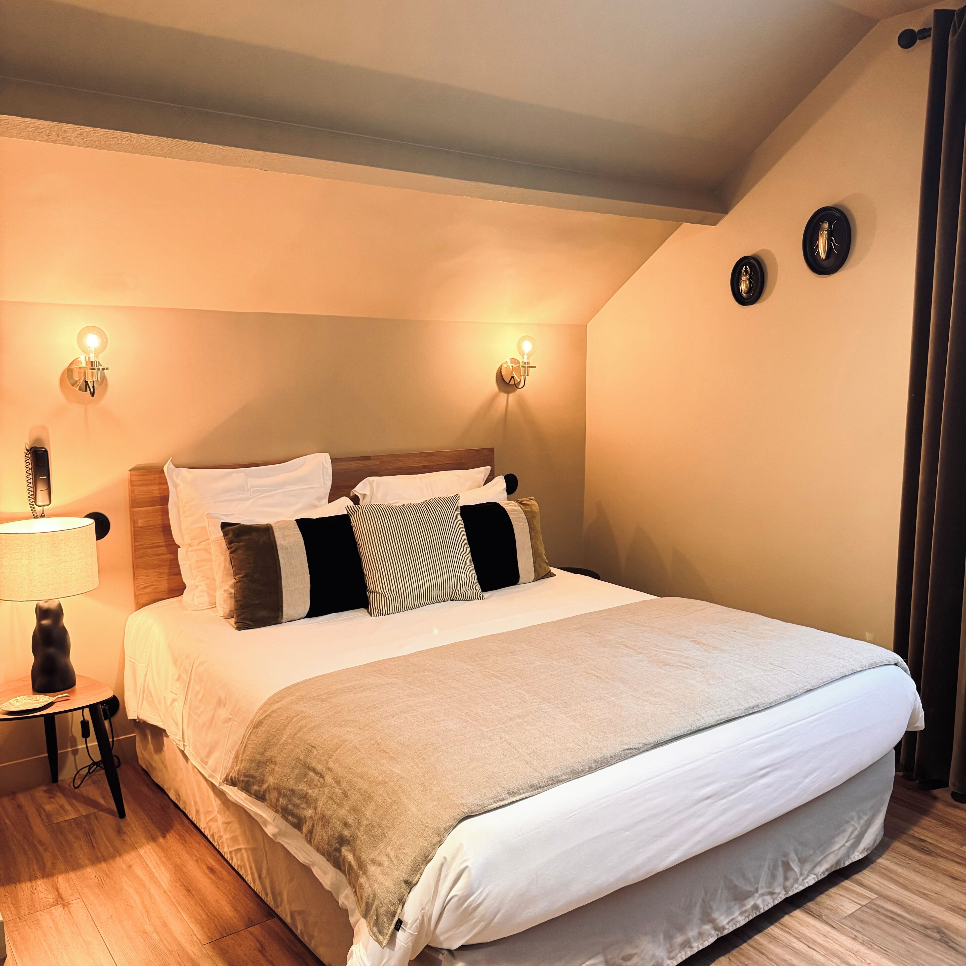 A bedroom with a large bed, two bedside lamps, a bedside telephone, and a small table with a lamp.