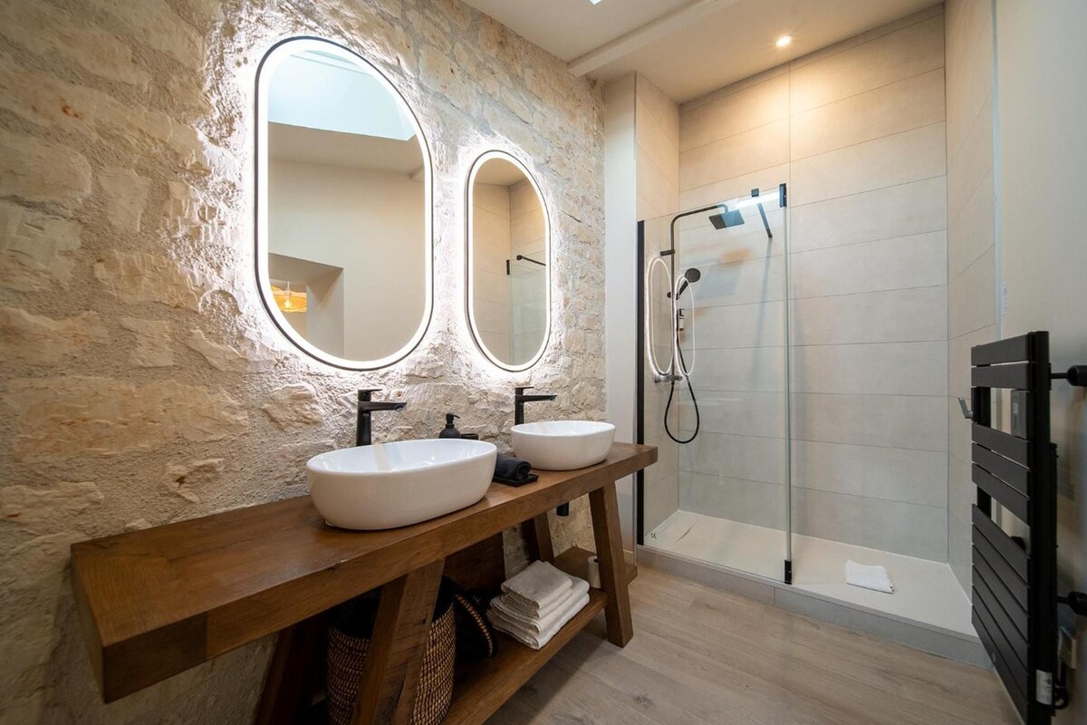 A bathroom with two sinks, a mirror, and a shower.