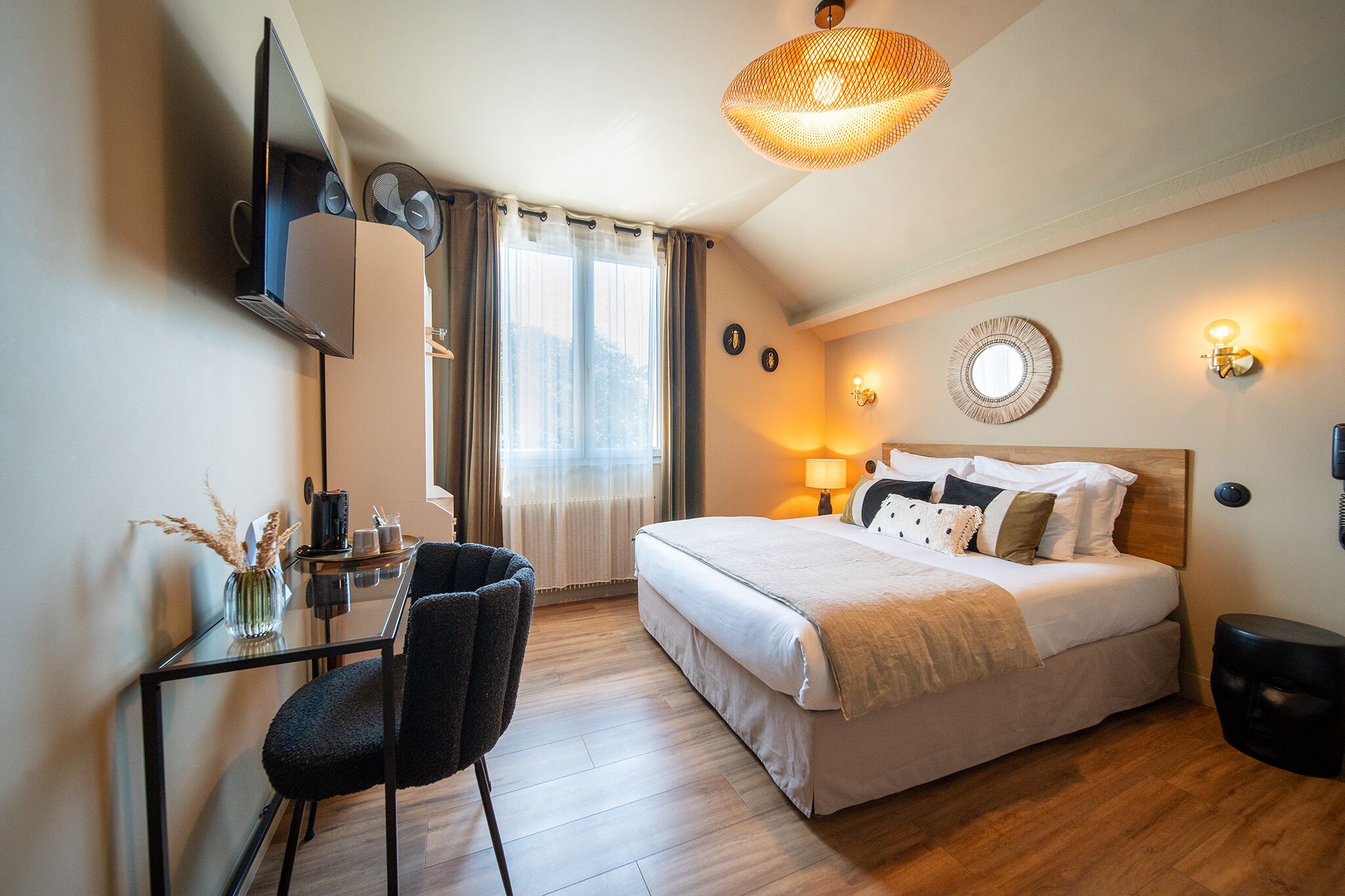 Ein Hotelzimmer mit einem Bett, einem Schreibtisch, einem Stuhl, einem Fernseher, einer Lampe und einer Wandleuchte.