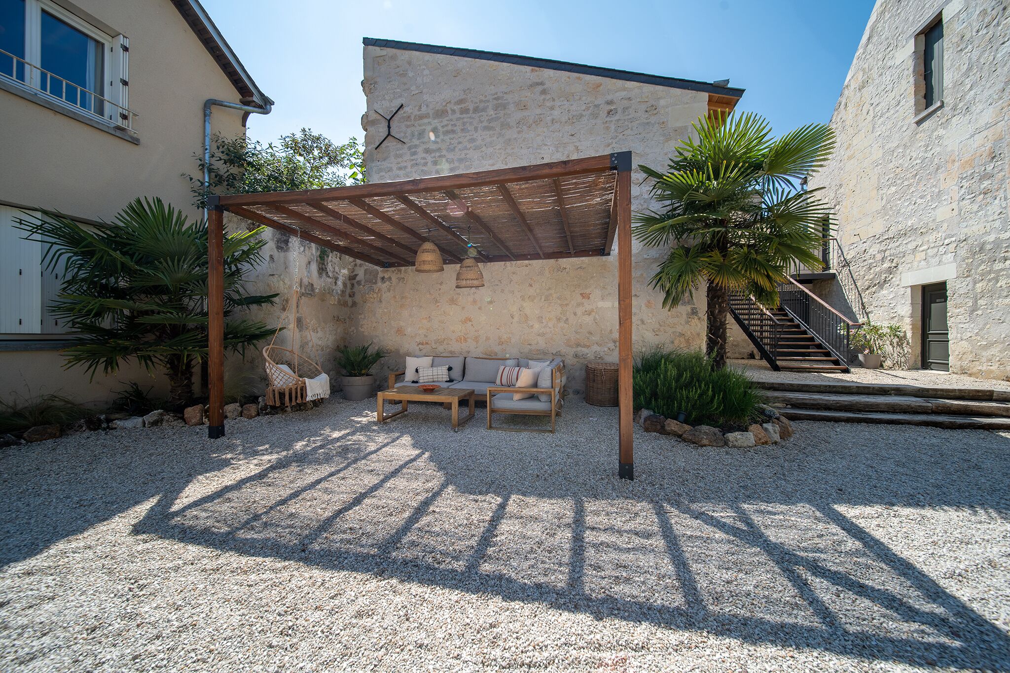 Un espace extérieur aménagé avec une pergola en bois, un canapé et une table, le tout abrité.