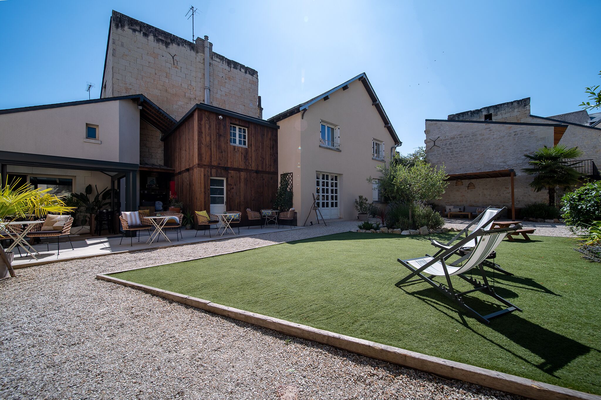 Un patio con césped artificial, mobiliario exterior y un edificio con fachada de piedra.