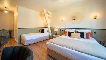 Habitación de hotel con dos camas, una silla, una mesita y una lámpara de pared.