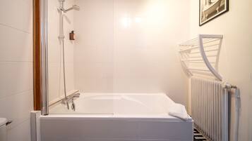 Un baño moderno con ducha acristalada, bañera blanca y suelo con estampado blanco y negro.