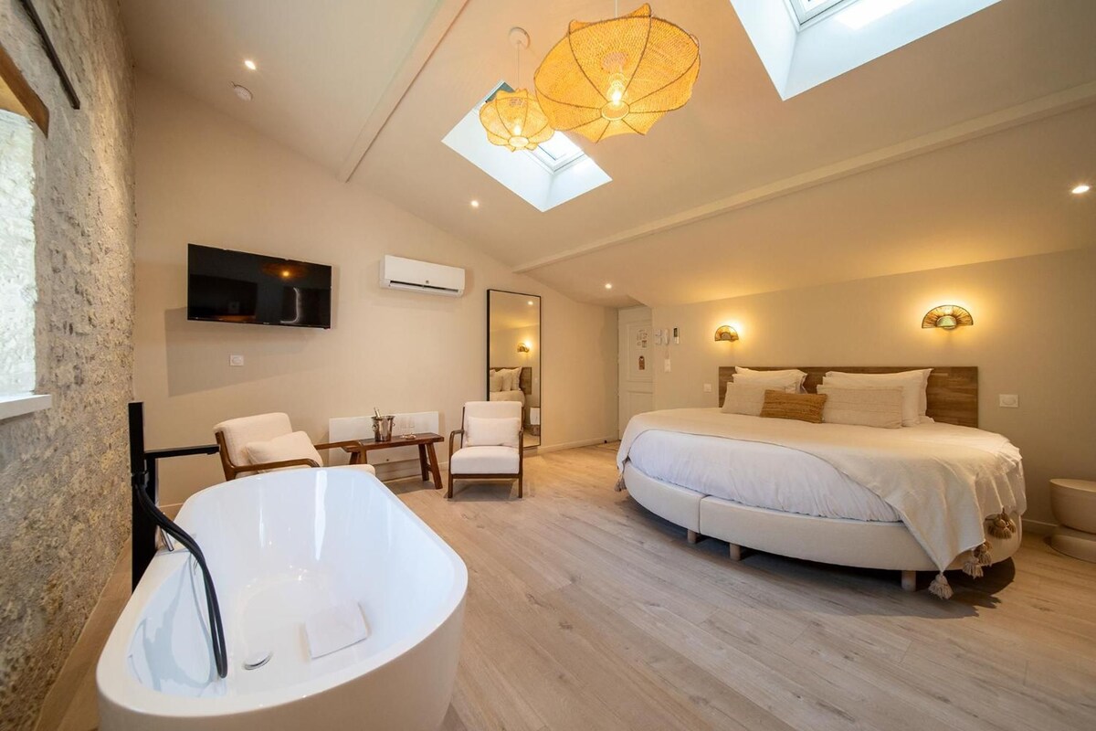 Une chambre moderne avec un grand lit, une baignoire et une fenêtre de toit.