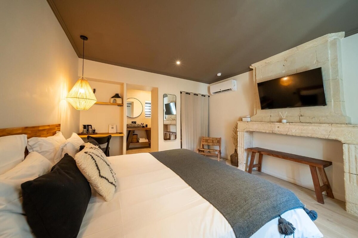 Una habitación de hotel con una cama grande, un escritorio, un televisor y una chimenea.