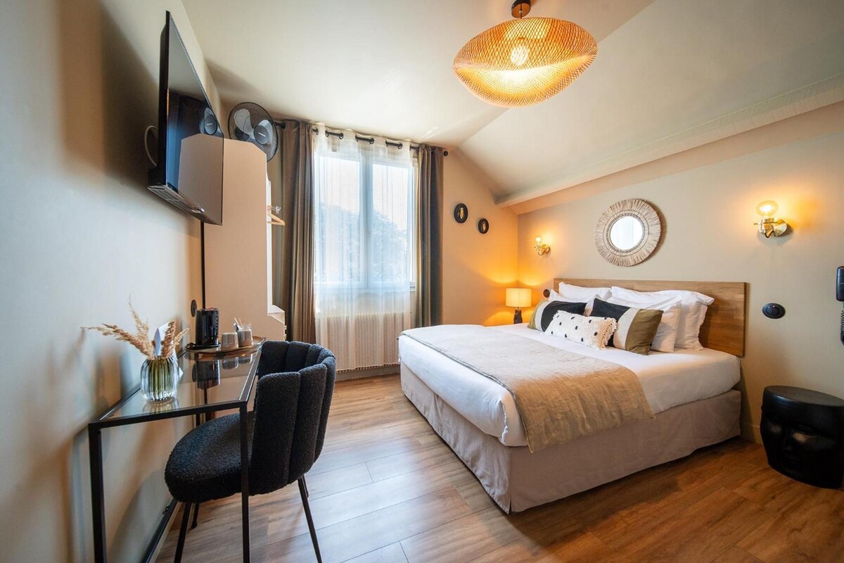 A hotel room with a bed, bedside table, lamp, and a television mounted on the wall.