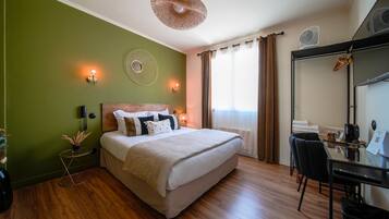 Habitación de hotel con cama, escritorio, silla, ventilador y teléfono en la pared.