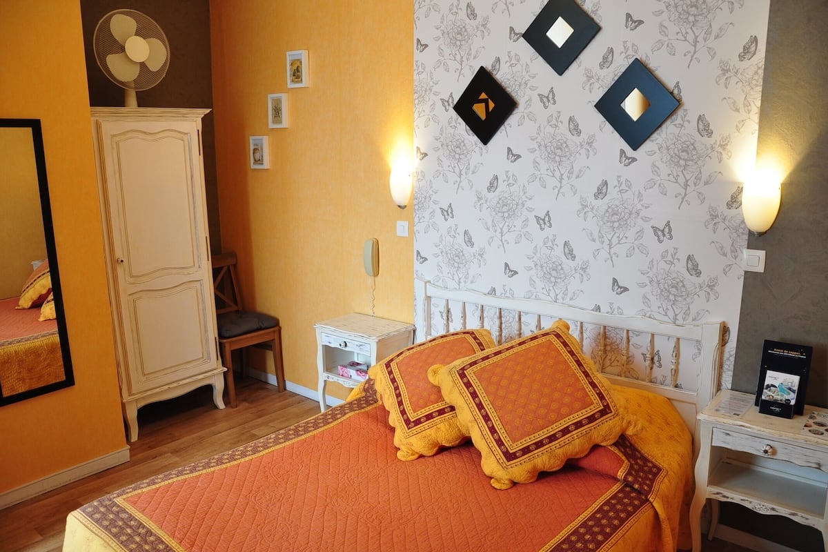 A bedroom with a bed, a nightstand, a dresser, and a wall with butterfly decals.