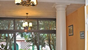 An indoor dining area with tables and chairs, a chandelier, and large windows overlooking a courtyard. - Hôtel Select (Salon-de-Provence)
