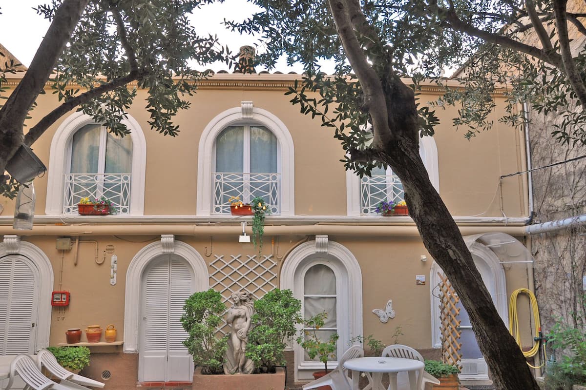 A building with arched windows, outdoor seating, and a statue.
