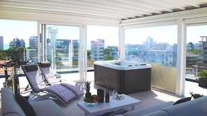 A balcony with a hot tub, lounge chairs, and a table with fruits and drinks. - Hotel Rossini (Lignano Sabbiadoro)