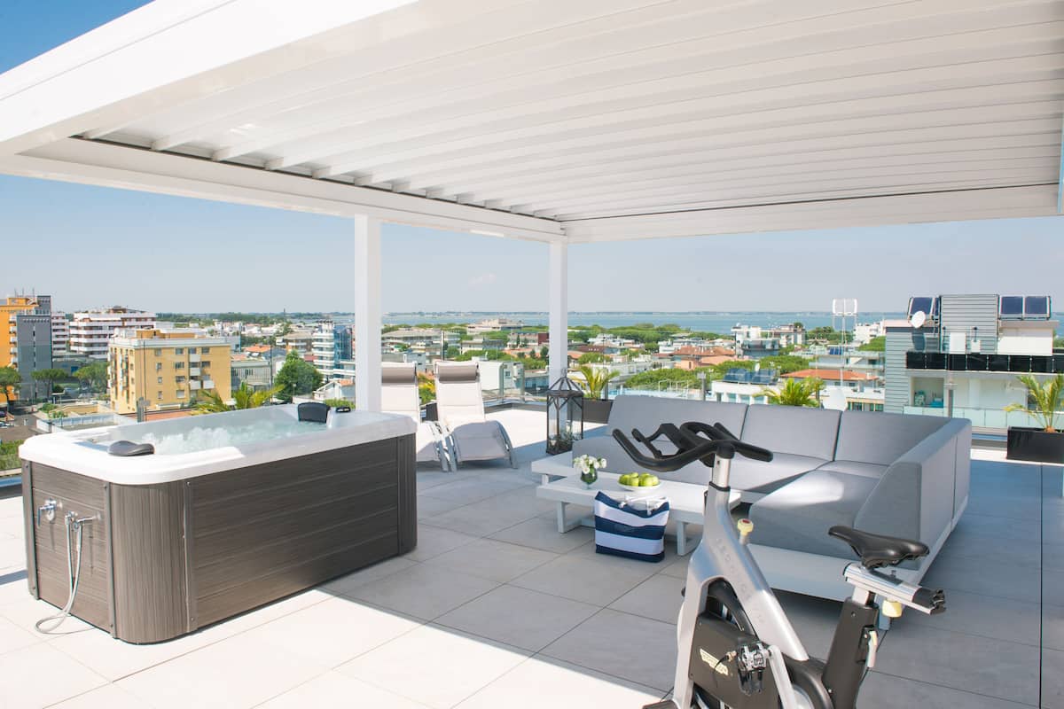 A rooftop terrace with a hot tub, seating area, and exercise bike.