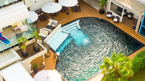 A rooftop pool area with lounge chairs, umbrellas, and a small waterfall feature. - Hotel Rossini (Lignano Sabbiadoro)