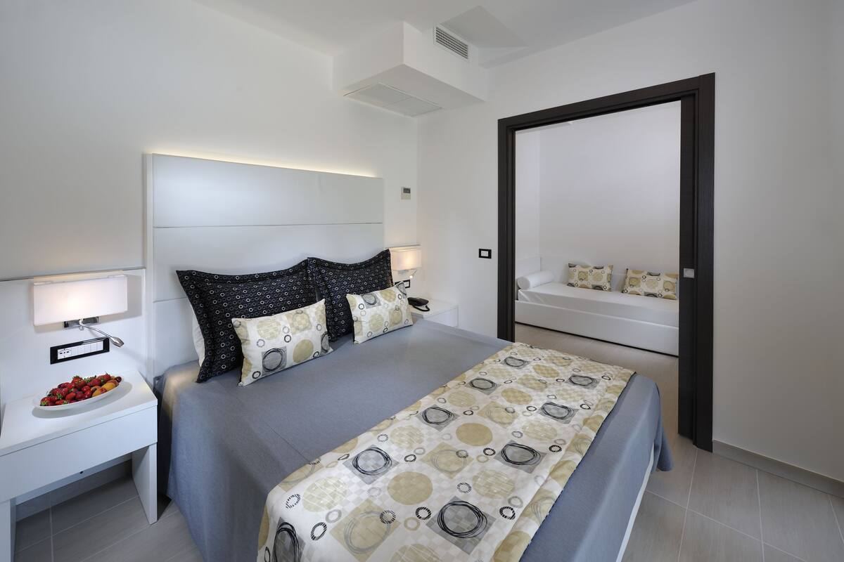 A modern bedroom with a bed, bedside tables, and a mirror.