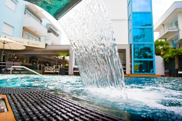 Una fuente de agua con una cascada frente a un edificio con un letrero que dice "Cafeteria Corner".