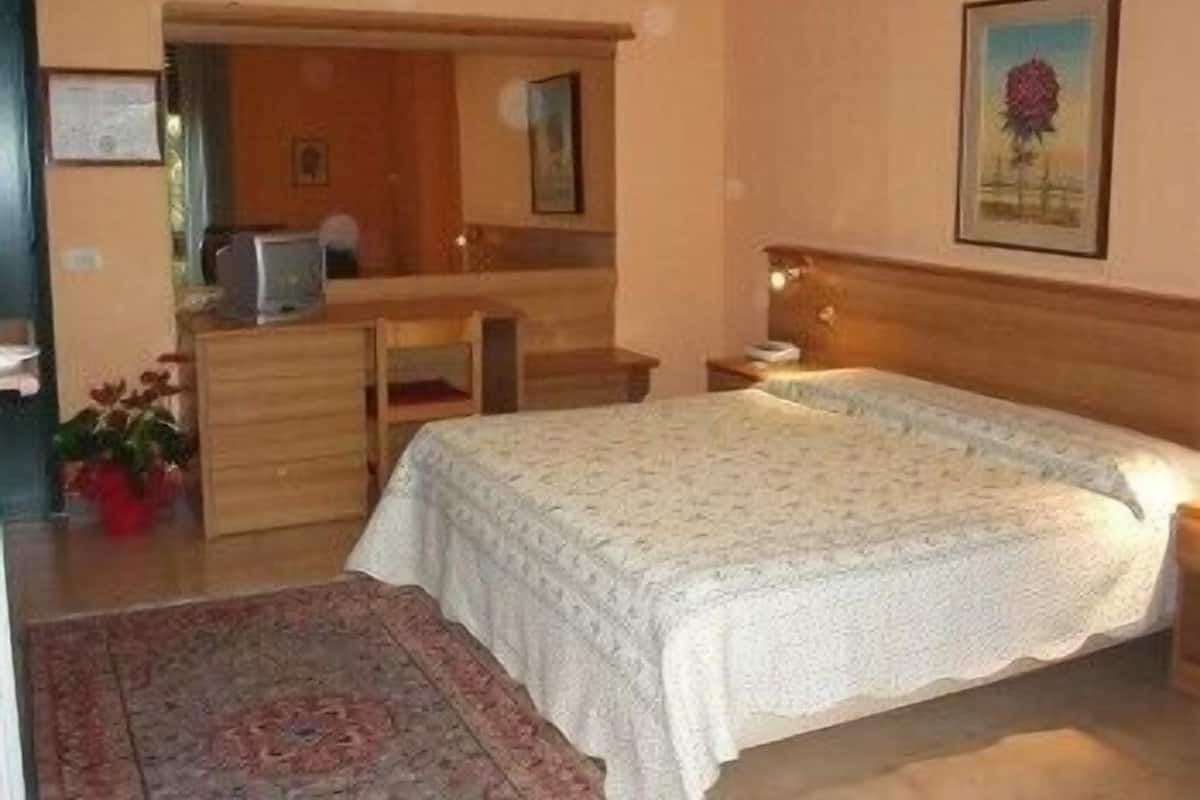 Un dormitorio con cama, escritorio, silla, cómoda y espejo.