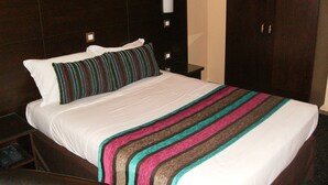 A hotel room with a large bed, a dark wooden headboard, a nightstand with a lamp, and a wardrobe. - Hôtel du Val de Seine (Mantes-la-Jolie)