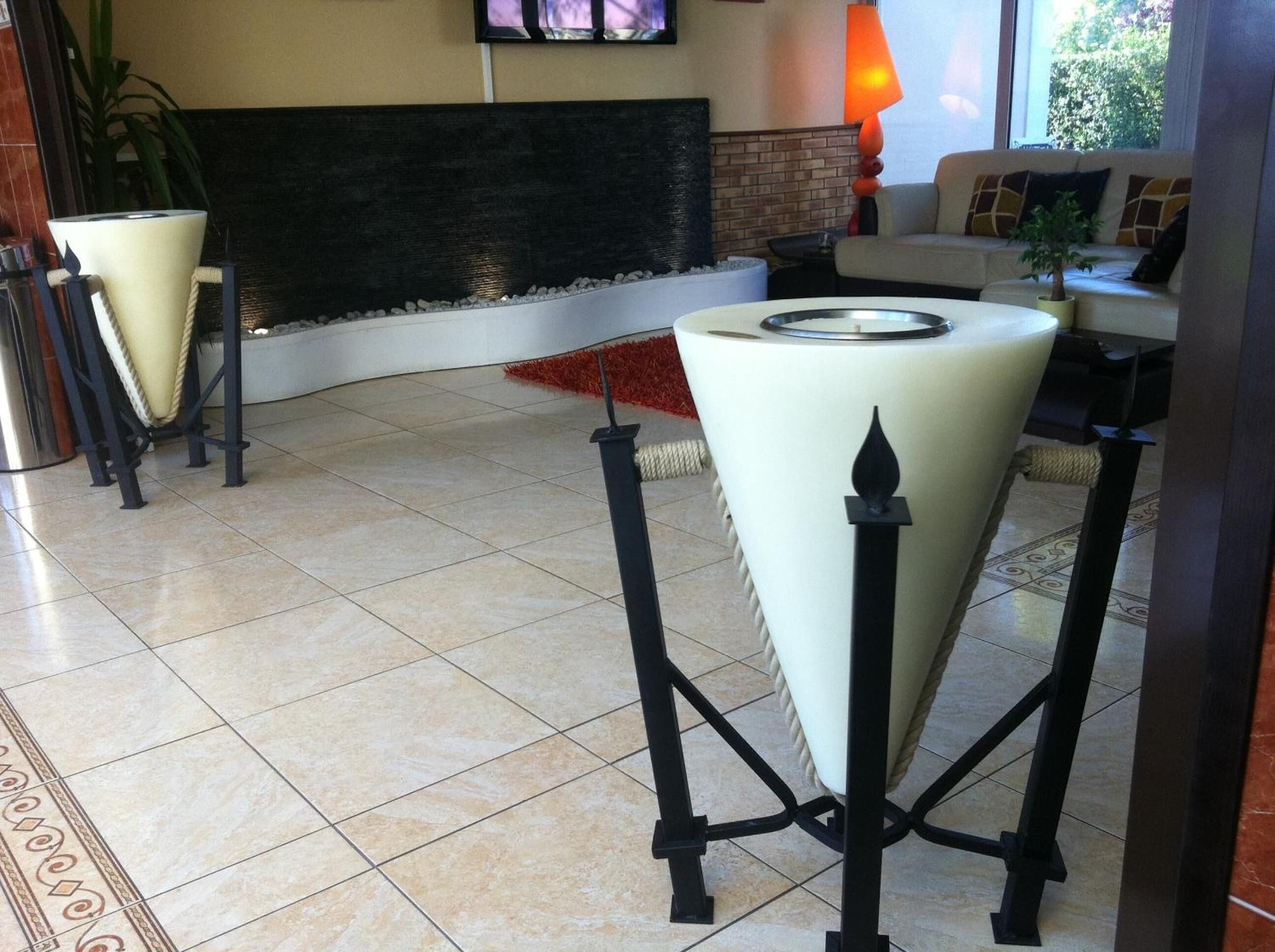 A modern lobby with a tiled floor, a fireplace, a sofa, and a small table with a candle.