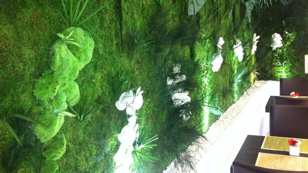 A room with a moss-covered wall, a small table with a vase, and a seating area. - Hôtel du Val de Seine (Mantes-la-Jolie)