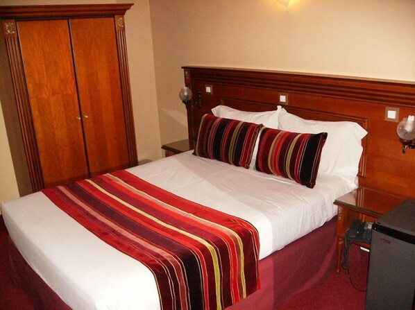 A hotel room with a large bed, wooden headboard, and a wardrobe. - Hôtel du Val de Seine (Mantes-la-Jolie)