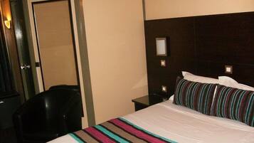 Una habitación de hotel con una cama, una silla, una mesita de noche y una puerta.