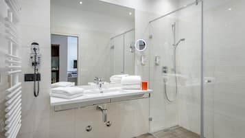 A modern bathroom with a glass-enclosed shower, a vanity with a mirror, and a towel rack.