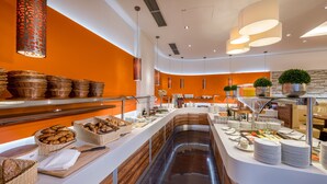 Una presentación de buffet moderna con diversos alimentos y cestas, un área central de servicio y una pared de acento naranja brillante.