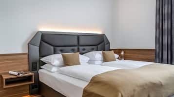 Una habitación de hotel moderna con una cama grande, una mesita de noche con una revista y una lámpara de pared.