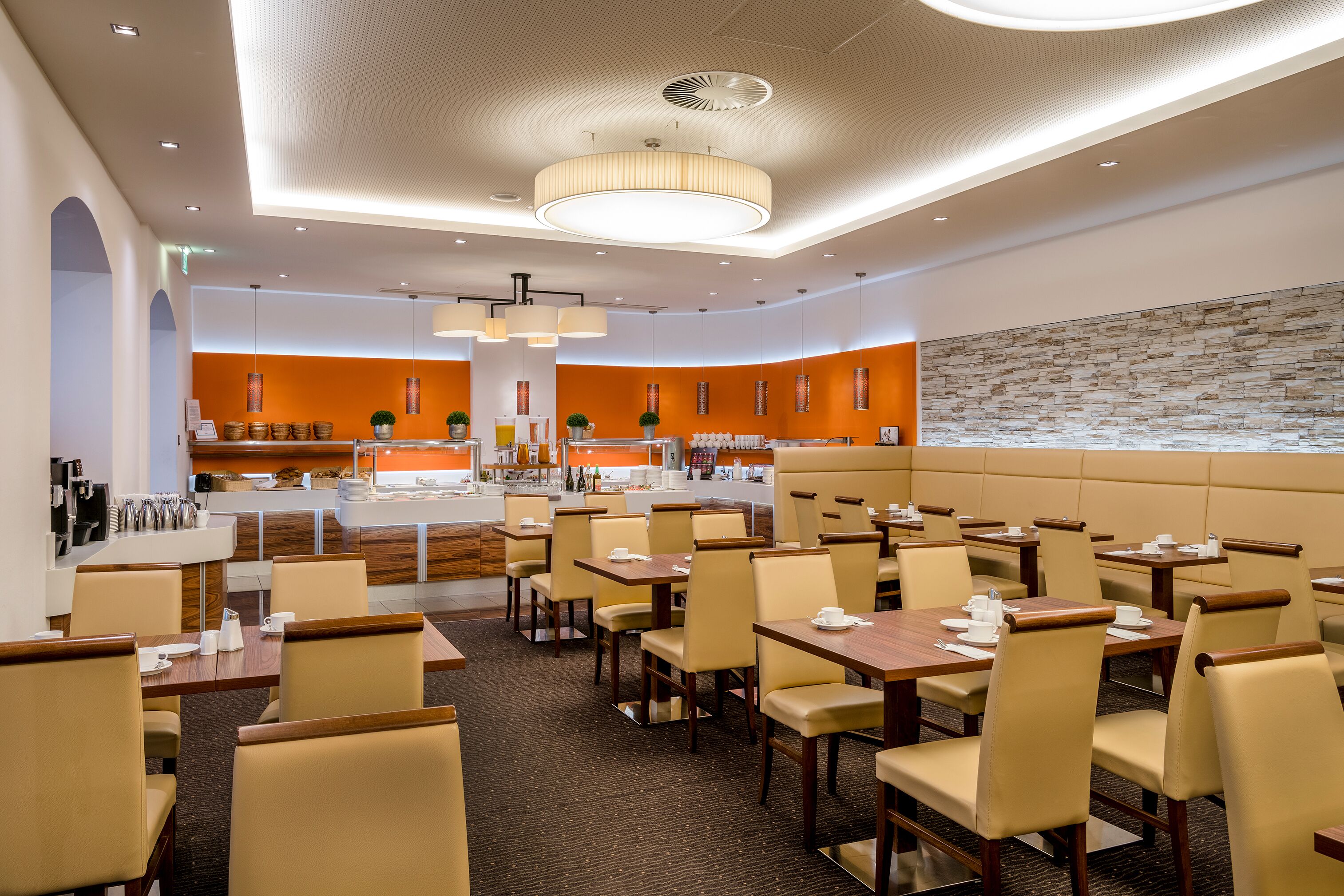 A modern restaurant with a central bar, booths, and a stone accent wall.